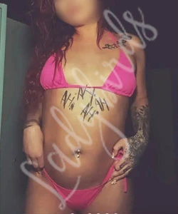 Woman posing in a pink string bikini with tattoos.