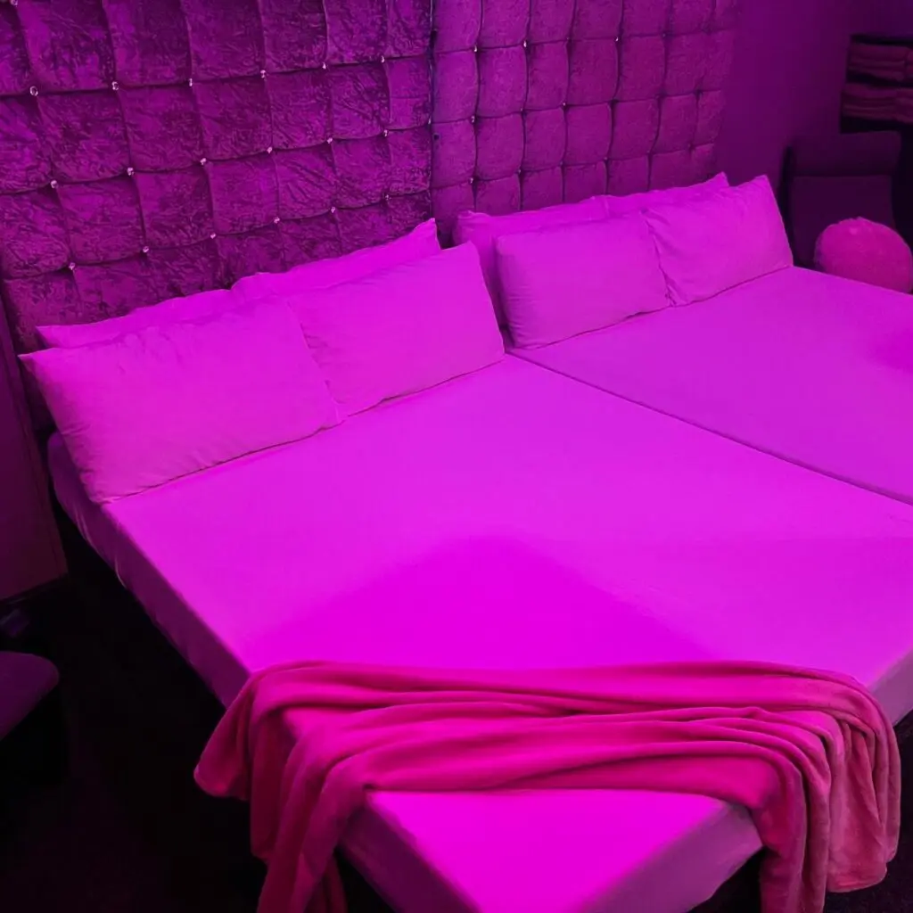 Pink-lit private guest room with double bed at Ladybirds Manchester