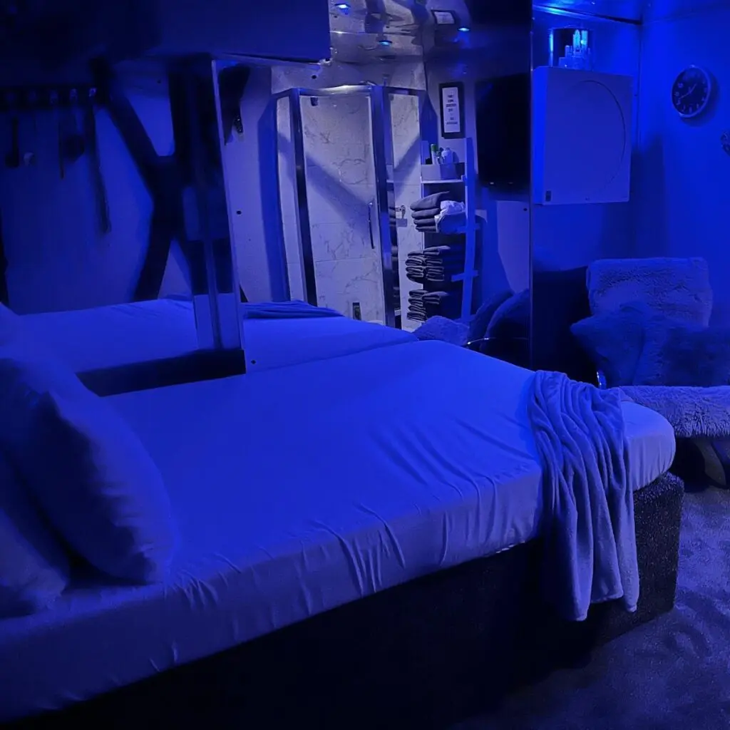 Blue-lit private guest room with double bed at Ladybirds Manchester