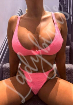 Woman wearing bright pink lace bra and thong on stairs